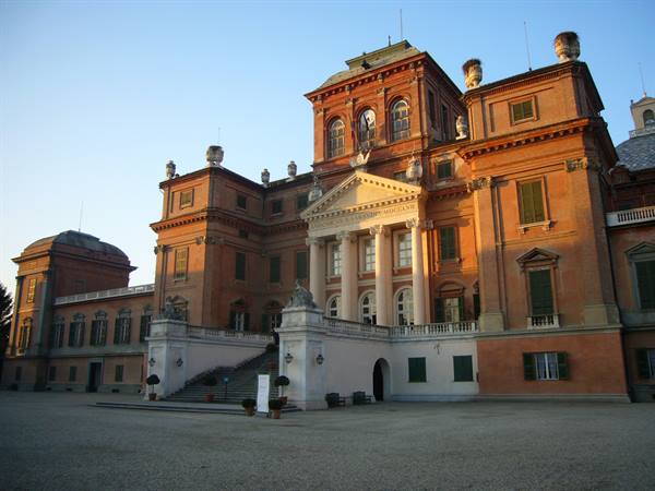 Racconigi Castle brick facade, white staircase, warm morning light on the courtyard