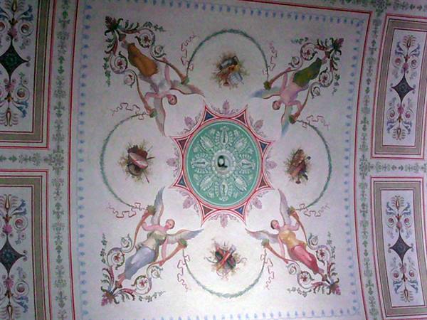 Frescoed ceiling with angels and floral motifs around a central green medallion