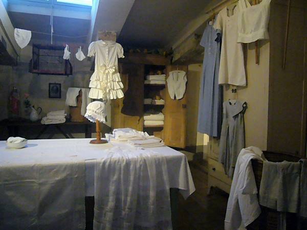 Vintage laundry room with white garments hanging, folded linens and natural light