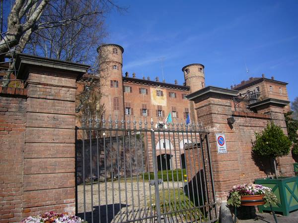 Brick castle with cylindrical towers, wrought iron gate and flower pots