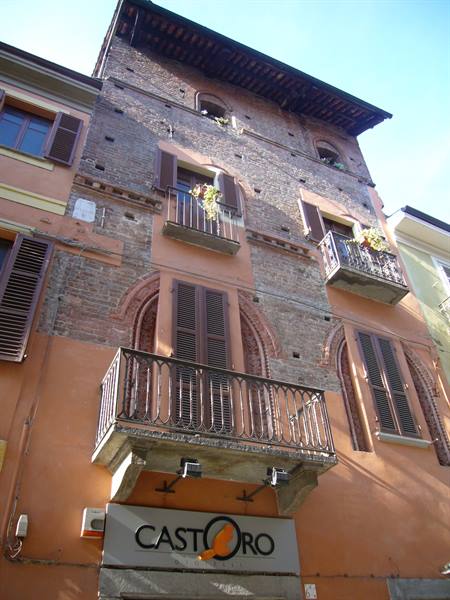 Brick building with wrought iron balconies and Castoro sign under blue sky
