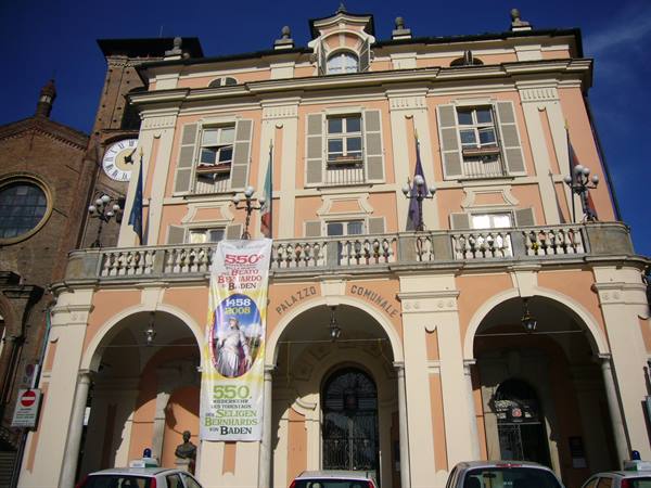Pink town hall with arcades and banner, beside clock tower