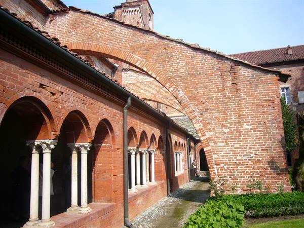 Red brick cloister with arches and white marble columns, daylight