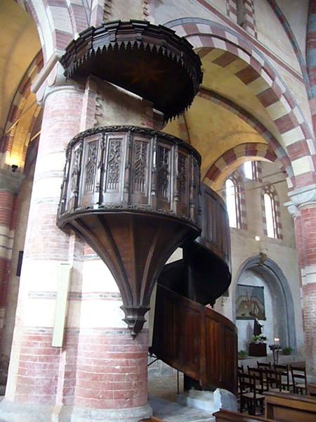 Carved wooden pulpit on a brick column inside a church