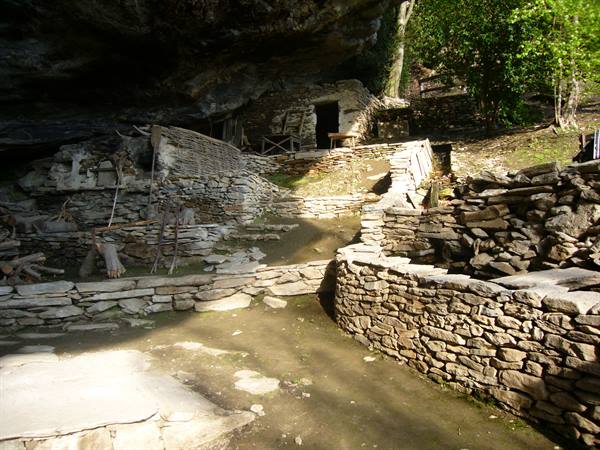 Ancient stone hamlet sheltered beneath a huge rock overhang