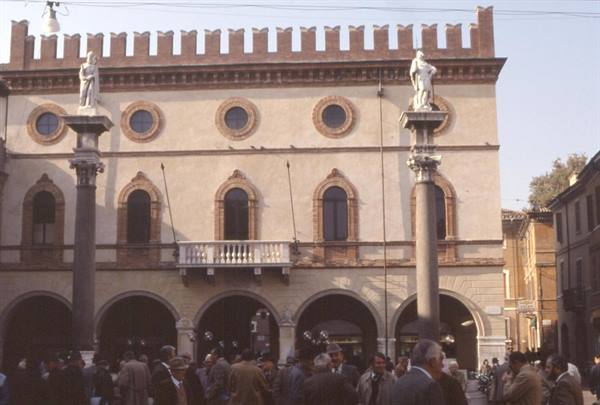 Ravenna town hall with battlements and statue-topped columns, crowd below