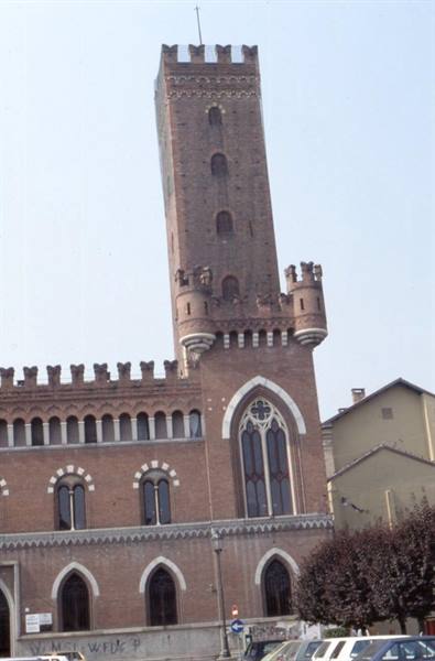 Crenellated brick tower on Gothic palace in Asti, parked cars below