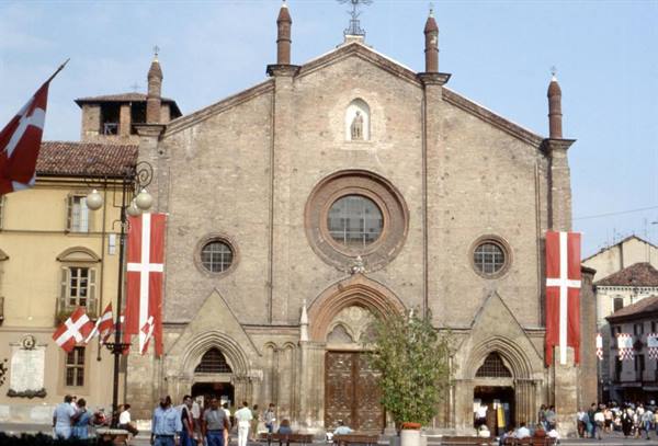 Brick facade of Asti Cathedral with cross banners on the square