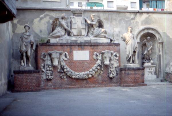 Stone statues and sculpted ox heads on a brick courtyard wall