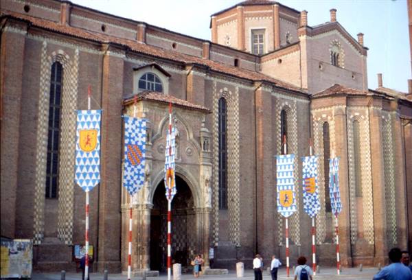 Asti Cathedral with brick facade and heraldic banners raised in the square