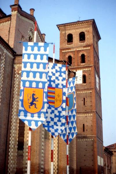 Heraldic blue and white banners in front of Asti Cathedral's brick bell tower