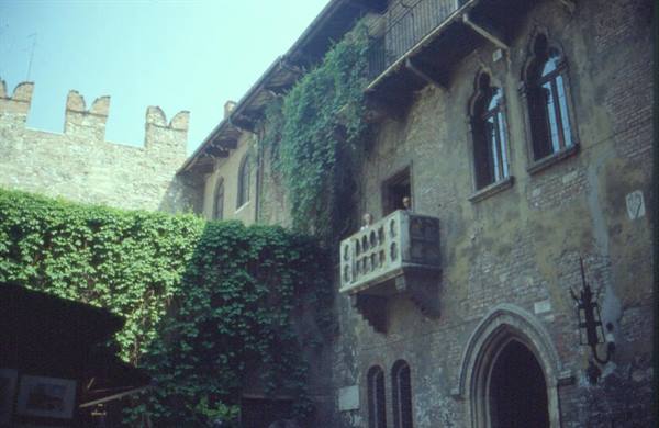 Juliet's House in Verona: people on the stone balcony, ivy-covered walls