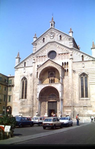 Romanesque facade of Verona Cathedral under blue sky, cars parked in the square