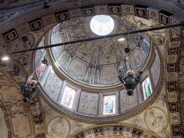Baroque dome with white stuccoes and stained glass windows inside a church