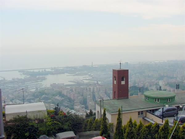 Brick bell tower overlooking Genoa harbor and foggy city rooftops