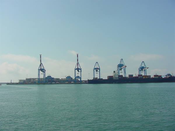 Container ship docked at the pier with blue cranes