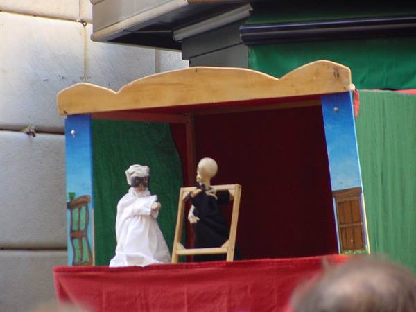White puppet and wooden skeleton on the red stage of a street puppet theater