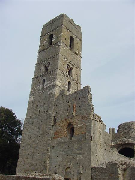Romanesque stone bell tower of San Rabano abbey, ruins under grey sky