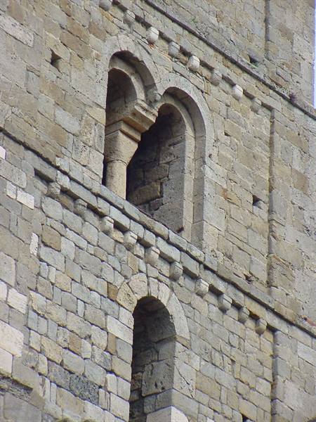 Romanesque stone mullioned window on medieval facade, daylight