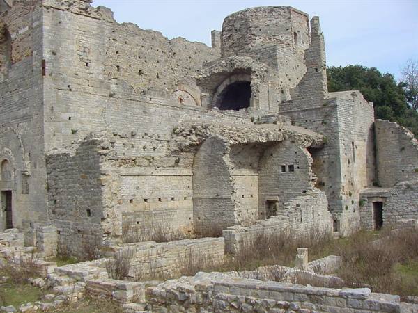 Ruins of a medieval stone abbey with unfinished arches and apse