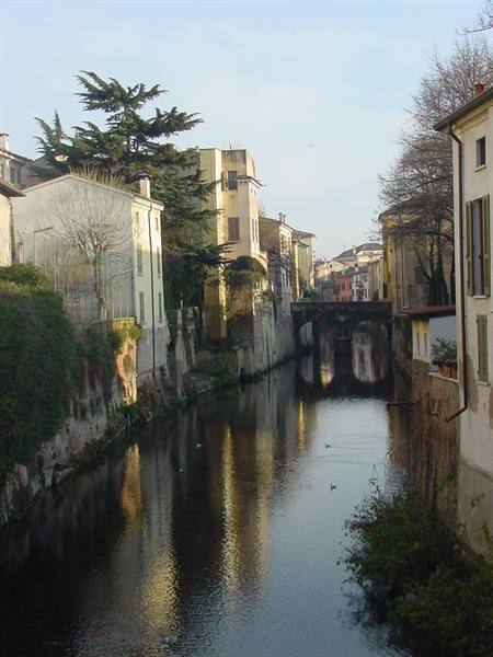 colorful houses reflected in the canal with stone bridge in Treviso