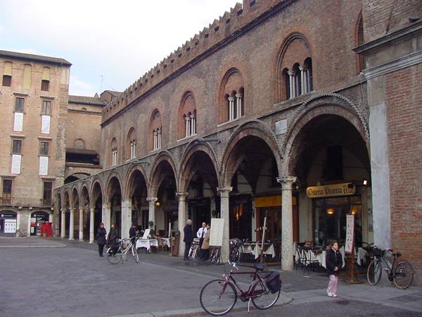Medieval brick arcades with café tables and bicycles, Piazza delle Erbe, Mantua
