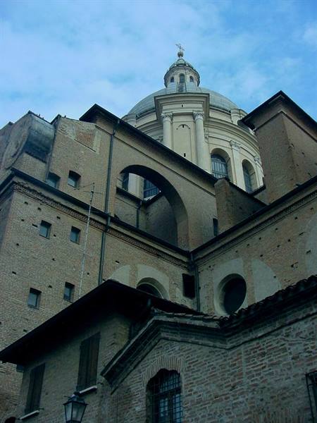 Baroque dome rising above old brick buildings under blue sky