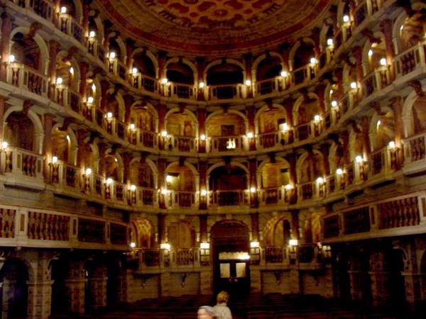 Inside the Teatro Farnese in Parma, wooden arcaded tiers lit by lamps