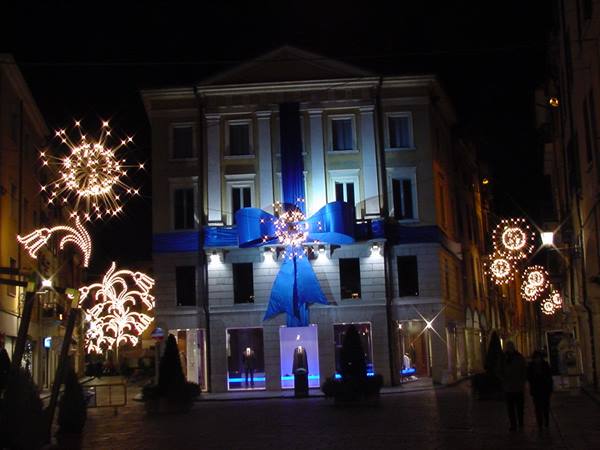 Neoclassical building decorated with illuminated blue bow and Christmas lights at night
