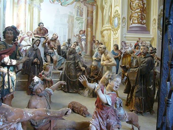 Chapel with life-sized painted statues, robed monks amid dramatic figures