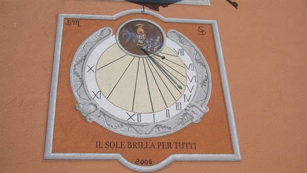Painted sundial on ochre wall, Roman numerals, motto 'The sun shines for everyone'