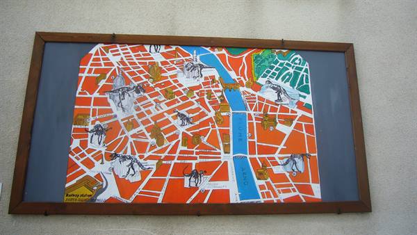 Painted map with dinosaur skeletons among streets, wooden frame on wall