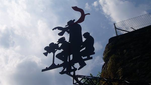 Black metal sculpture of a director and cameramen against a cloudy sky