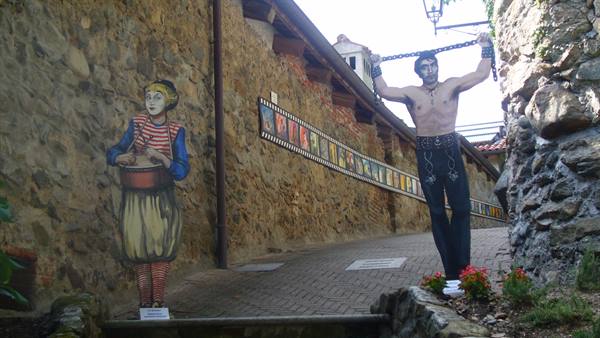 Life-size painted cardboard figures along a brick alley with stone walls