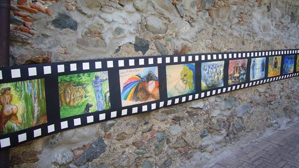Film strip with colorful drawings displayed on a rustic stone wall