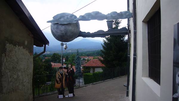 Metal moon and clouds sculpture between houses, poet cutouts leaning on the railing