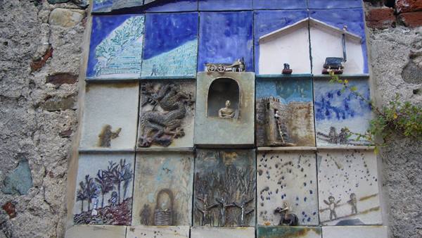 Carved ceramic tile panel with scenes and figures on a stone wall