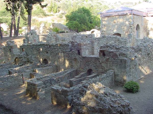 Stone ruins of ancient buildings with arches, trees and sunlight