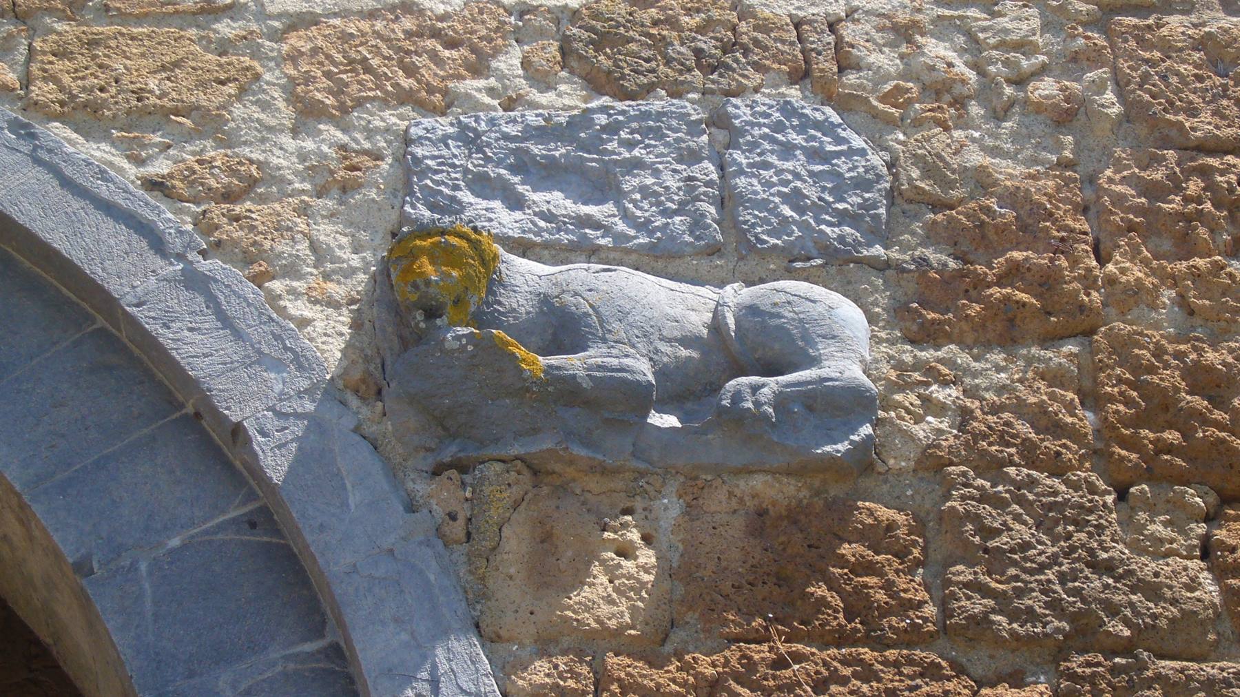 Leone scolpito in pietra incastonato sulla muratura sopra un arco