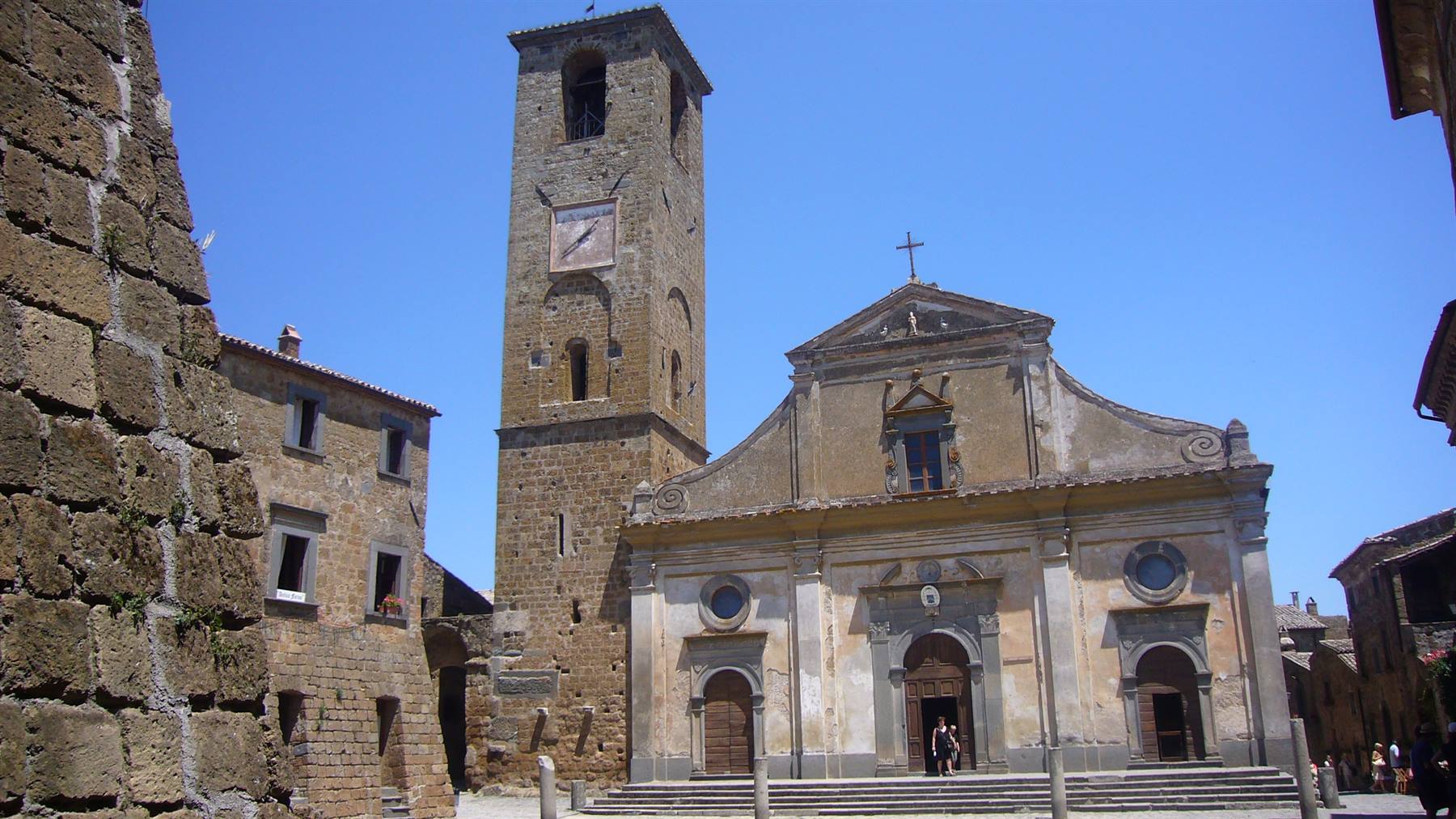 Duomo di Civita di Bagnoregio, facciata in pietra e campanile sotto il sole
