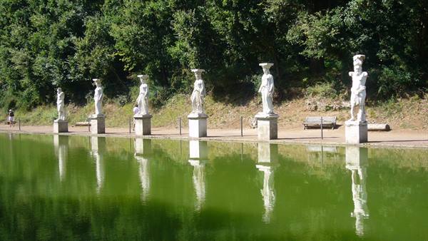 Marble statues reflecting in the green pond of Bomarzo's Park of Monsters