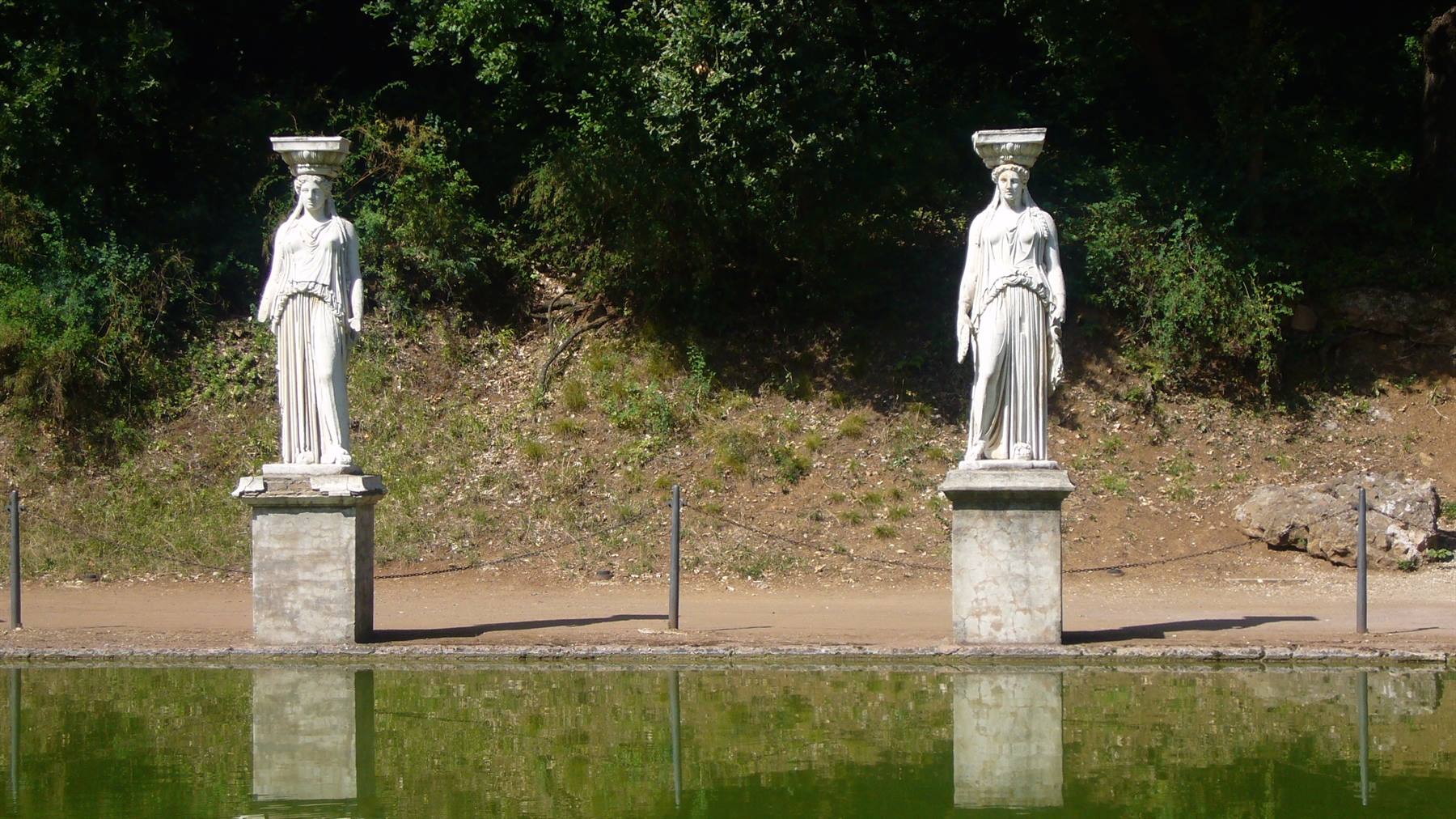 Due statue di cariatidi in marmo riflessioni nello stagno di Villa Adriana