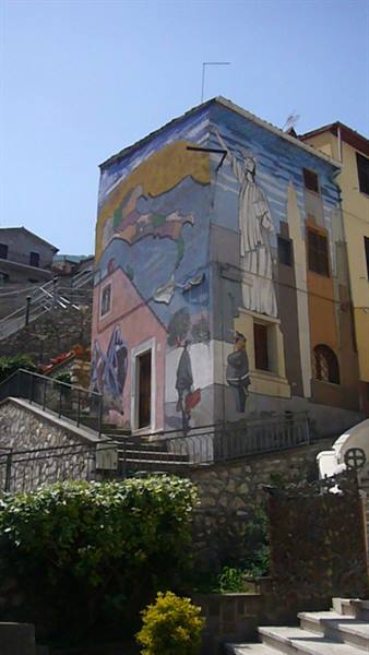 House covered in a colorful mural, stone stairways beneath a clear blue sky