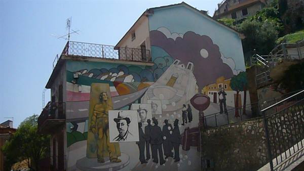 Mural with painted figures and faces on a village house facade