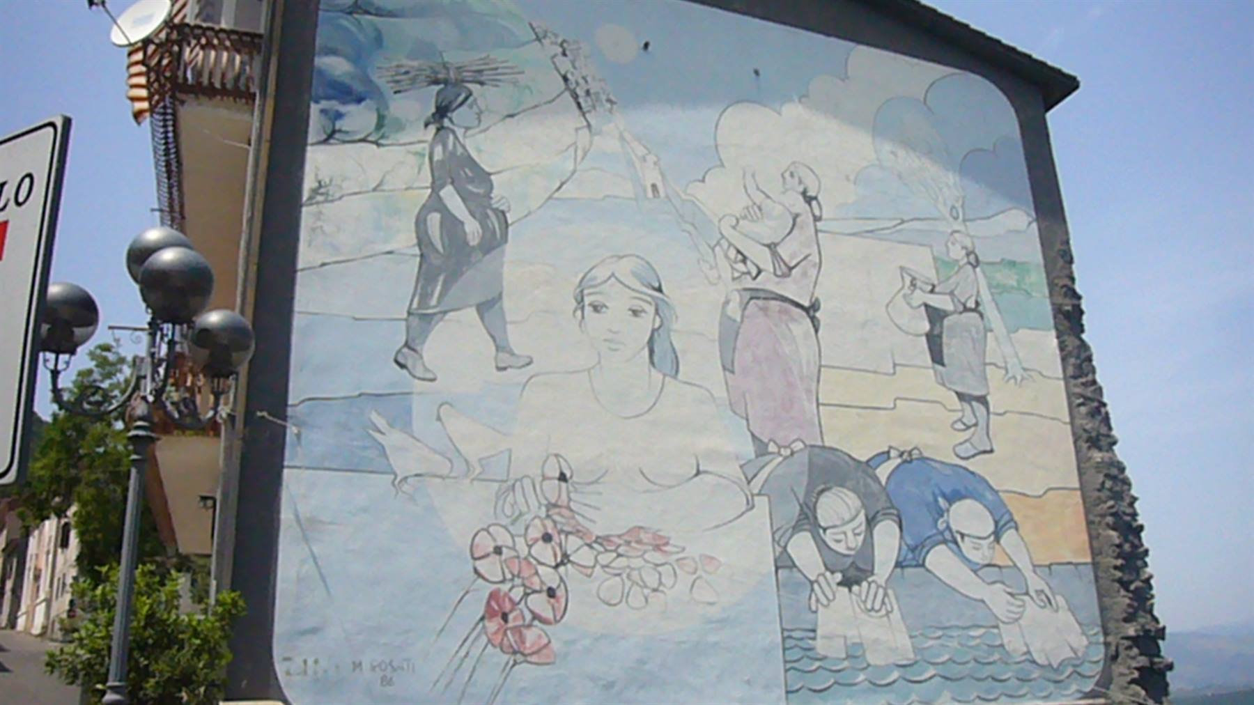 Murale su muro di casa: donne che lavano panni e camminano, luce diurna