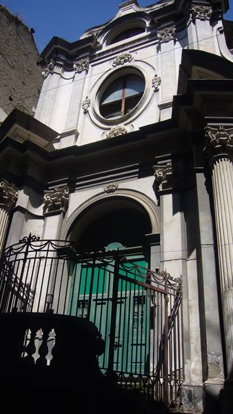 Baroque facade with round window and iron gate before green door