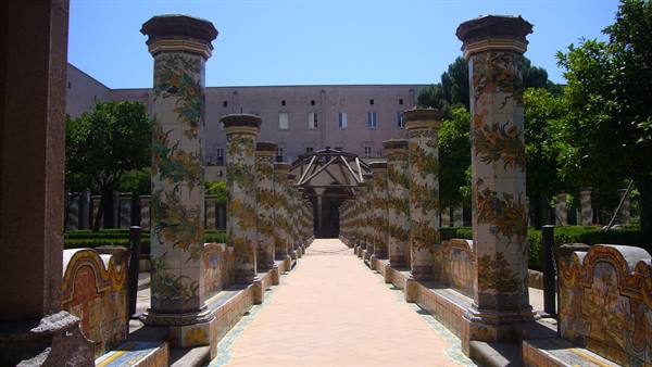 Santa Chiara cloister in Naples, majolica columns along the sunlit pathway