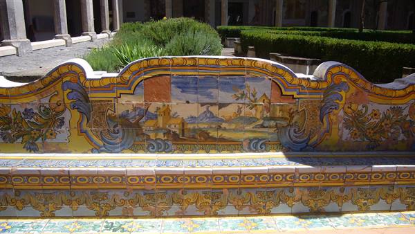 Majolica tiled bench with painted scenes in Santa Chiara cloister, sunlight