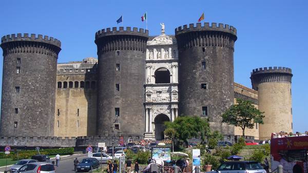 Castel Nuovo in Naples, dark stone towers and marble arch under sunny sky