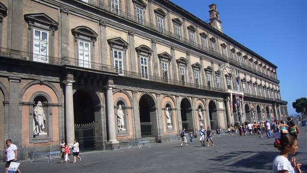 Royal Palace of Naples, stone facade with statues and tourists in Piazza del Plebiscito